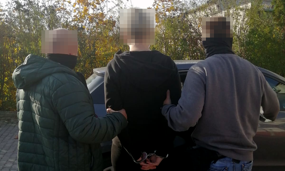 dwaj policjanci prowadzą zatrzymaną kobietę zakutą w kajdanki