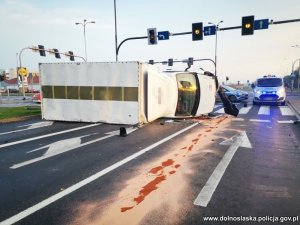 Na zdjęciu skrzyszowianie, sygnalizacja świetlna i samochód ciężarowy przewrócony na prawy bok leżący na pasach, obok dwa radiowozy policyjne