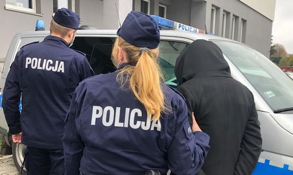 policjantka i policjant prowadzą zatrzymanego mężczyznę