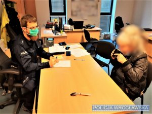 Na zdjęciu policjant oraz kobieta, której pomogli policjanci w biurze w komendzie policji siedzący przy biurku.