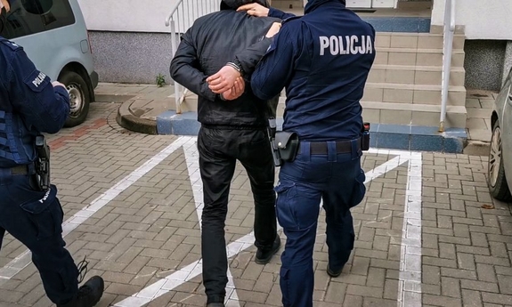 umundurowany policjant prowadzi zatrzymanego mężczyznę