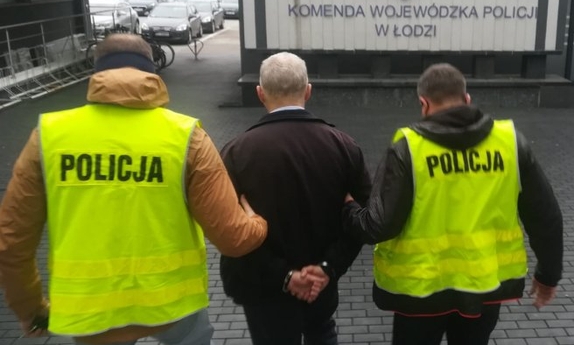 dwaj policjanci prowadzą zatrzymanego mężczyznę