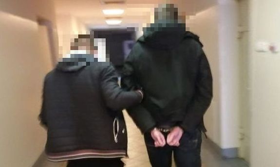 Na zdjęciu policjant w cywilnym ubraniu prowadzi korytarzem komendy Policji skutego w kajdanki zatrzymanego