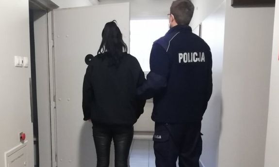 umundurowany policjant prowadzi zatrzymaną kobietę&quot;&gt;