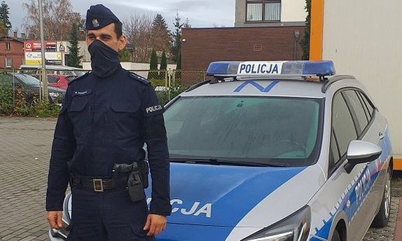 policjant stoi przed radiowozem