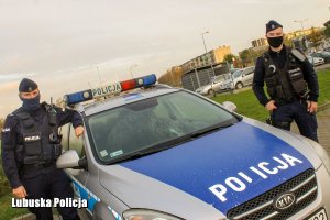 dwaj policjanci stoją obok radiowozu