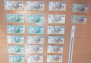 Na zdjęciu widoczne są rozłożone na biurku pieniądze w banknotach 500 zł, 200 zł i  100 zł