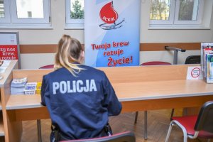 policjantka siedzi przy stoliku i wypełnia dokumenty