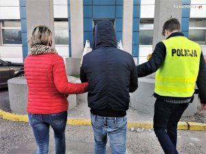 policjant i policjantka prowadzą zatrzymanego mężczyznę