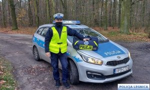 policjant stoi przy radiowozie