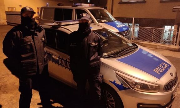 Na zdjęciu dwaj policjanci w mundurach, w tle dwa radiowozy