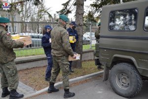 Policjantki i żołnierze wkładają paczki z żywnością do samochodu.