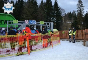 patrol przy wyciągu narciarskim i narciarze czekający w kolejce