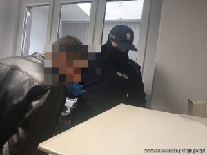 Na zdjęciu policjant bada zatrzymanego alkomatem