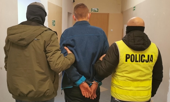 dwaj policjanci prowadzą zatrzymanego mężczyznę