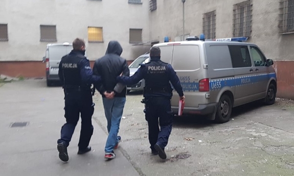dwaj policjanci prowadzą zatrzymanego mężczyznę
