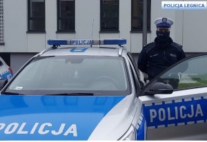 Na zdjęciu policjant ruchu drogowego stoi przy radiowozie