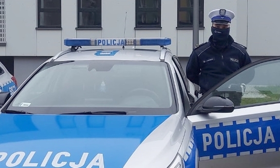 Na zdjęciu policjant ruchu drogowego stoi przy radiowozie