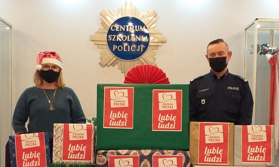 policjant i kobieta stoją za paczkami świątecznymi