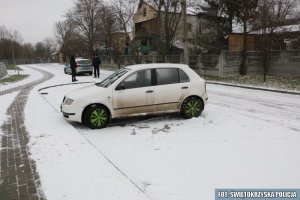 zaparkowana biała skoda, z tyłu widoczni stojący dwaj policjanci i policyjny radiowóz