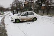 zaparkowana biała skoda, z tyłu widoczni stojący dwaj policjanci i policyjny radiowóz