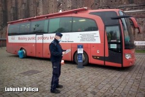 policjant stoi przy krwiobusie