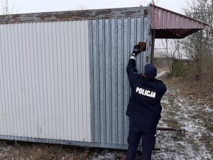 Policjant przyczepiający tabliczkę do kontenera