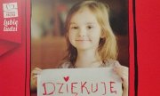 fragment plakatu w kolorze czerwony, na którym jest uśmiechnięta dziewczynka, trzymająca w ręce serce z napisem dziękuję