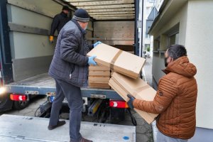 Mężczyzna podaje drugiemu mężczyźnie pudło z nielegalnymi papierosami