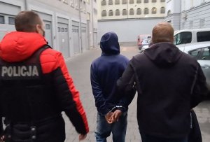 dwaj policjanci prowadzą zatrzymanego