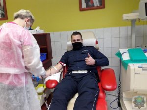 Policjant oddaje krew obok stoi pielęgniarka