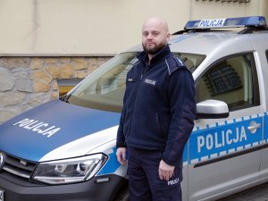 policjant stoi przy radiowozie