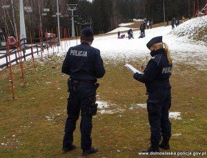 Na zdjęciu policjant i policjantka stojący na stoku narciarskim