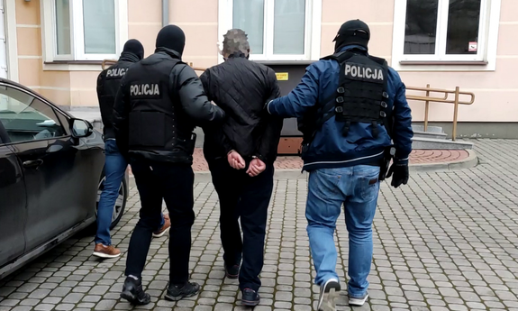 Policjanci prowadzą zatrzymanego