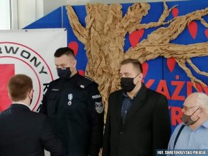 policjant otrzymuję gratulacje, obok inni krwiodawcy