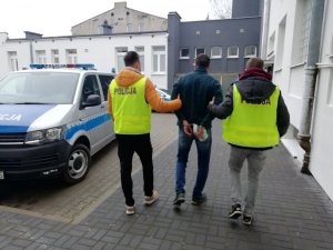 dwaj policjanci prowadzą zatrzymanego mężczyznę