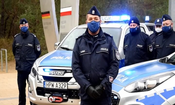 grupa policjantów przy radiowozach