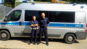 Policjantka i policjant stojący obok siebie przed radiowozem