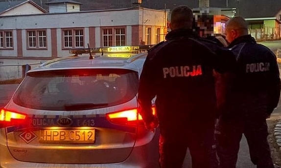 grupa policjantów z odnalezionym mężczyzną stoją obok radiowozu