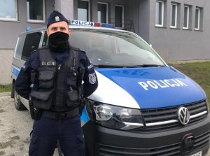 Policjant stoi przed radiowozem