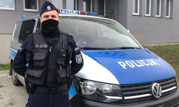 Policjant stoi przed radiowozem