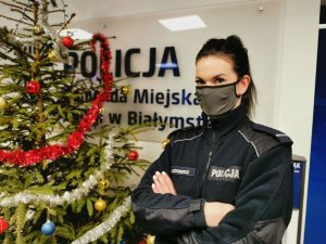Policjantka, brunetka w masce stojąca przy choince