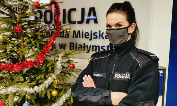 Policjantka, brunetka w masce stojąca przy choince