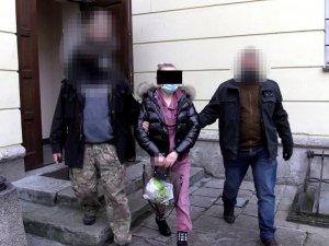 dwaj policjanci prowadzą zatrzymaną kobietę