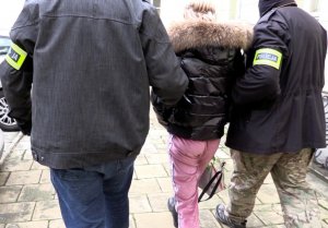 dwaj policjanci prowadzą zatrzymaną kobietę