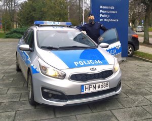 policjant stoi przy radiowozie policyjnym z otwartymi drzwiami