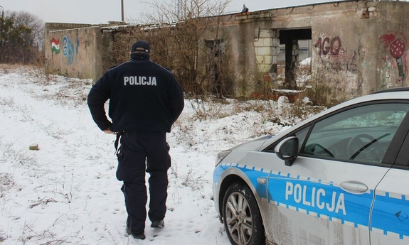 policjant idzie w kierunku pustostanu