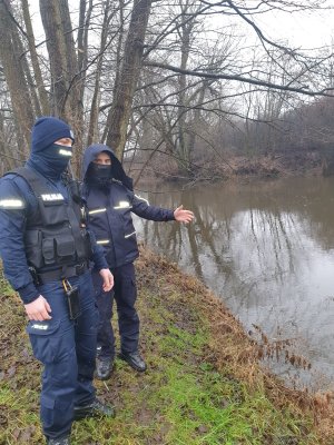 dwaj policjanci stoją na brzegu rzeki