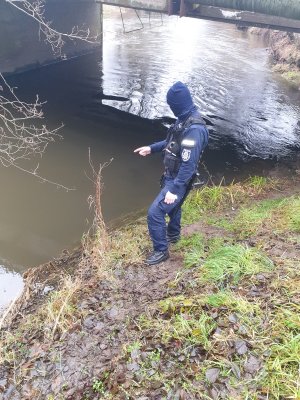policjant stoi na brzegu rzeki