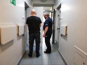 Policjant wprowadza zatrzymanego do celi
